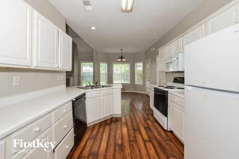 A kitchen with white cabinets and a white refrigerator.