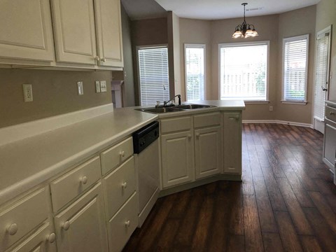 A kitchen with white cabinets and a wooden floor.