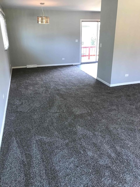 a carpeted living room with a gray carpet and a door to a balcony