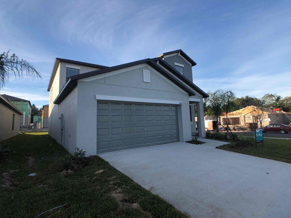 A two-story house with a garage door and a driveway.