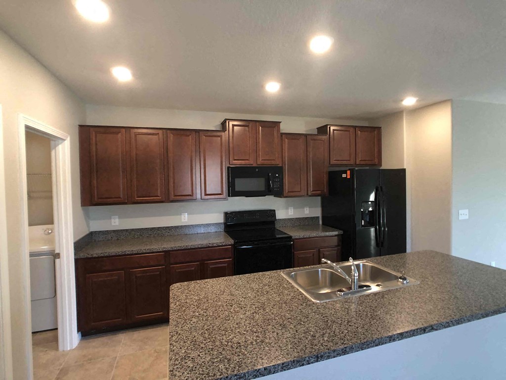 A kitchen with brown cabinets and black appliances.
