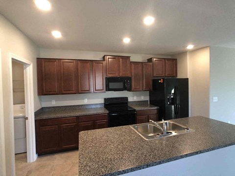 A kitchen with brown cabinets and black appliances.