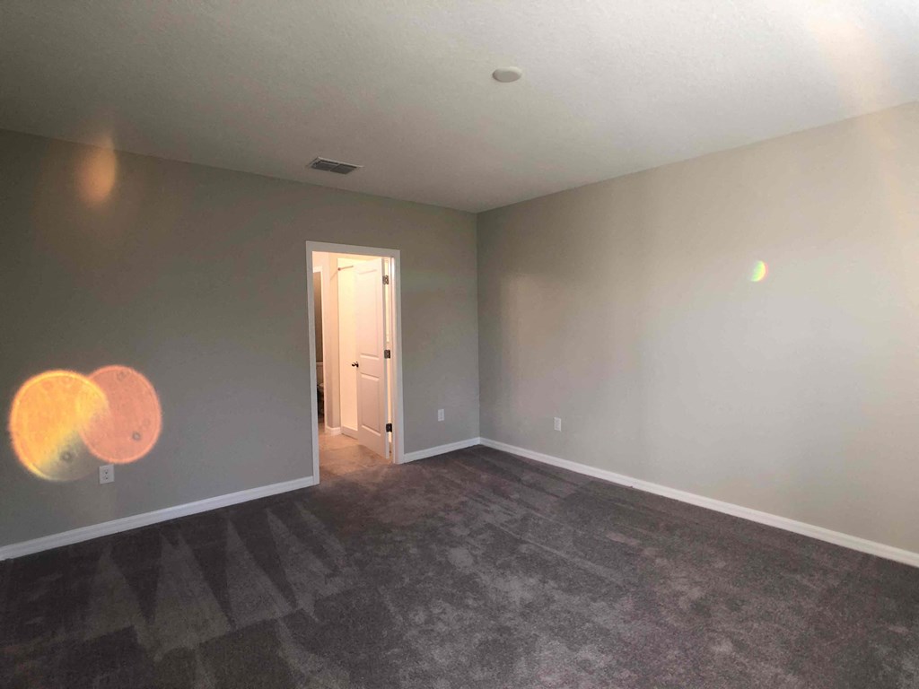 A room with a carpeted floor and a doorway leading to another room.