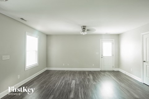 A spacious room with wooden flooring and a ceiling fan.