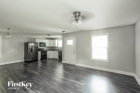 A spacious kitchen and living room with wood flooring and white walls.