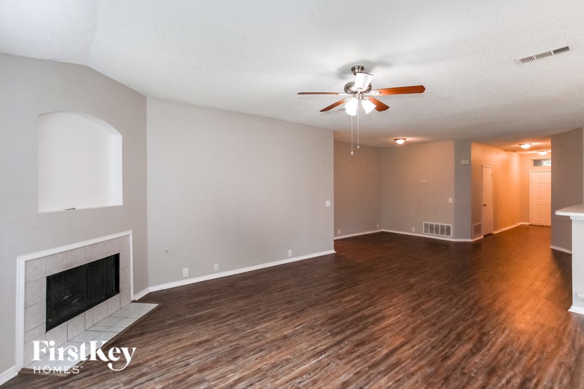 A spacious room with a fireplace and wooden flooring.