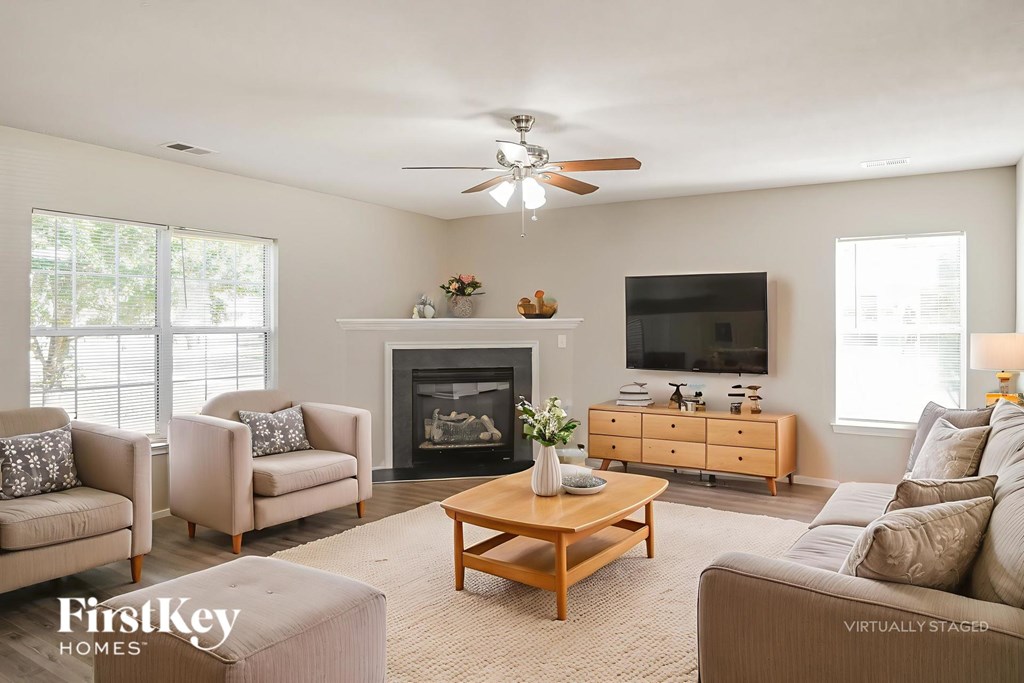 A living room with a fireplace, two chairs, a coffee table, and a television.