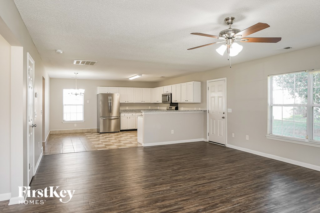 A spacious kitchen and living room with wooden floors and white walls.