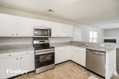 A kitchen with white cabinets and granite countertops.