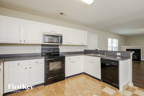 A kitchen with white cabinets and black appliances.