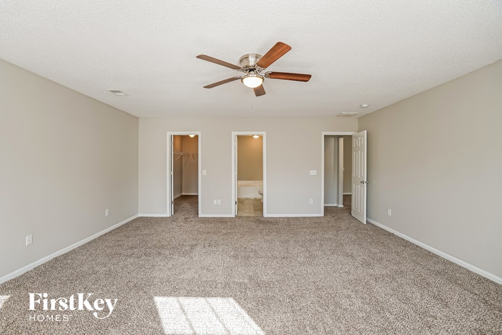 A spacious room with a ceiling fan and carpeted floor.