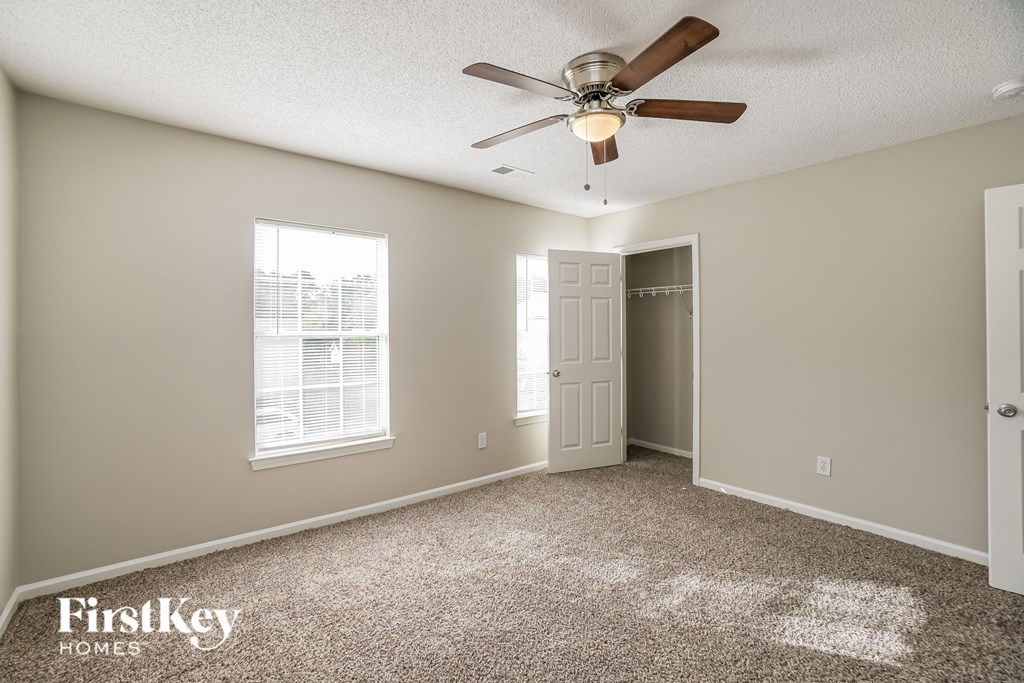 A room with a carpet floor and a ceiling fan.