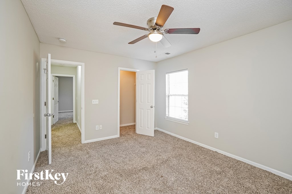 A room with a carpeted floor and a ceiling fan.