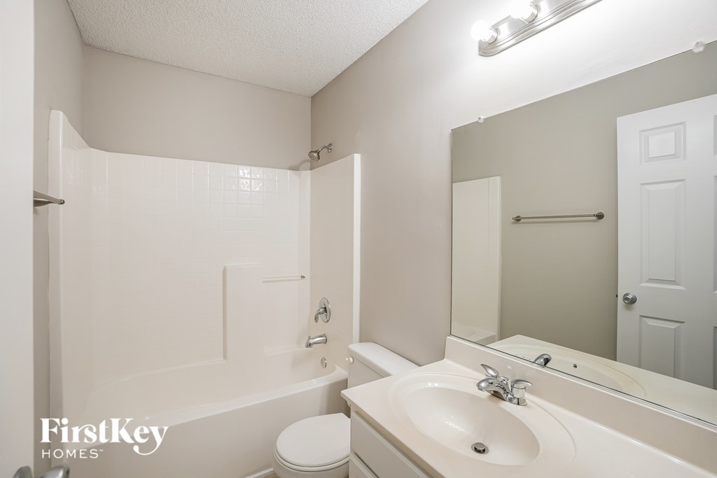 A white bathroom with a toilet, sink, and mirror.