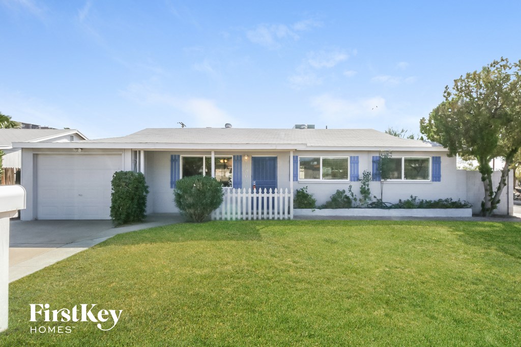 a white house with blue shutters and a lawn
