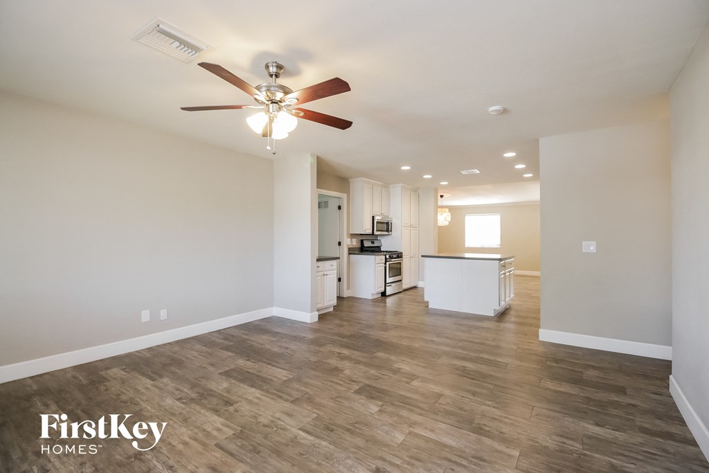 a living room with a ceiling fan and a kitchen