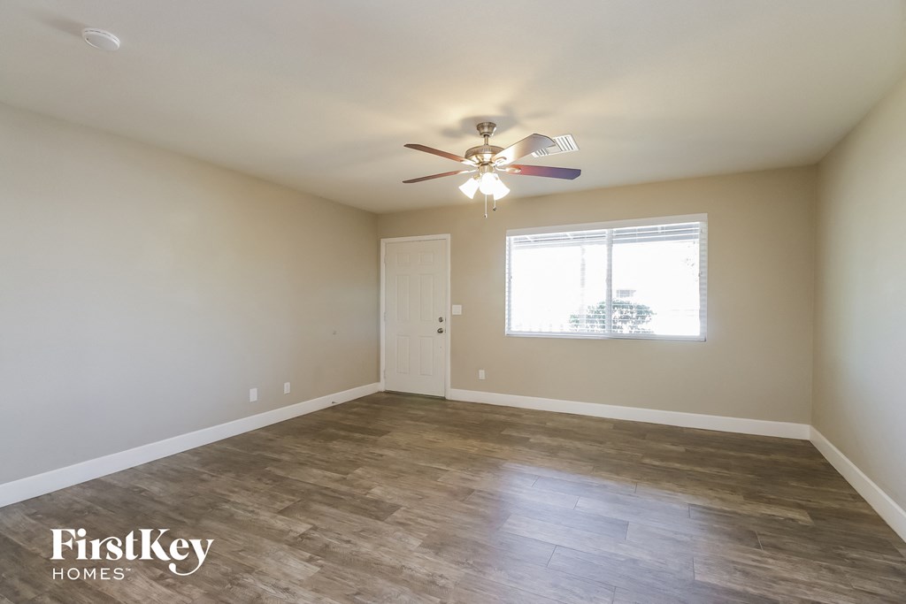 an empty room with a ceiling fan and a window