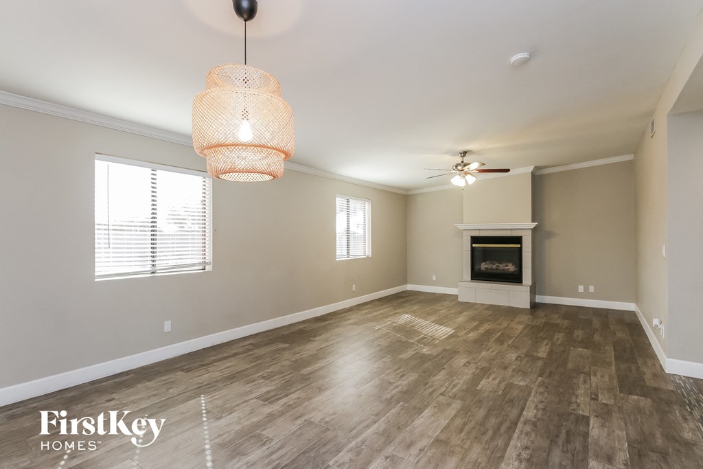 an empty living room with a fireplace and wood flooring