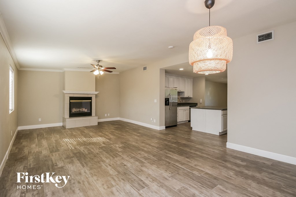 an empty living room with a fireplace and a kitchen