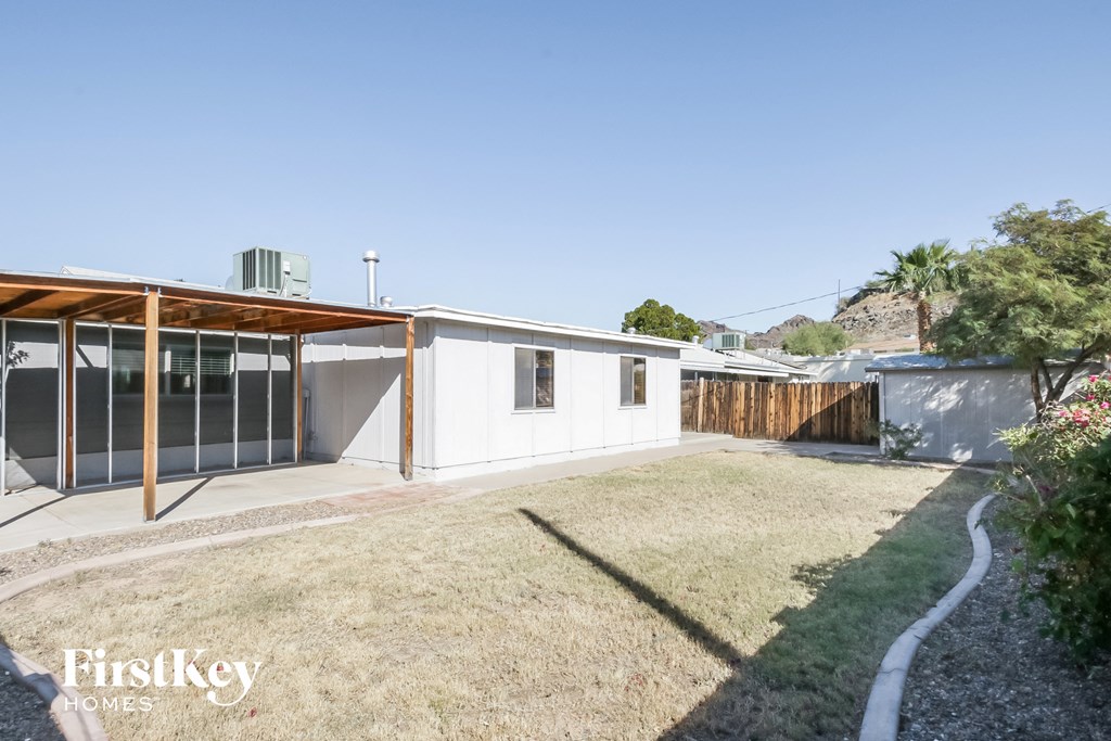 the backyard of a white house with a yard and a fence