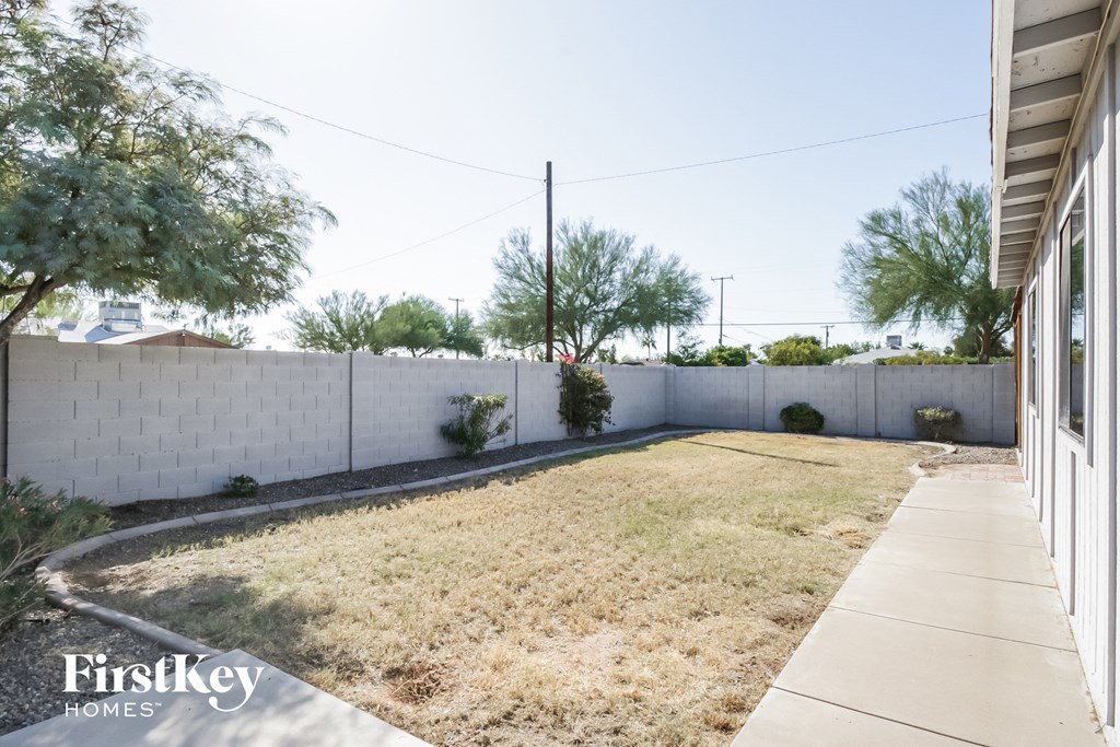 a yard with a white fence and a sidewalk and a house