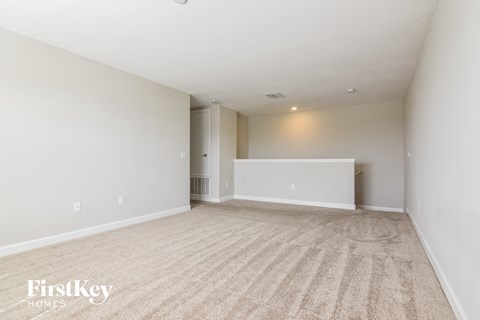 a spacious living room with carpet and white walls