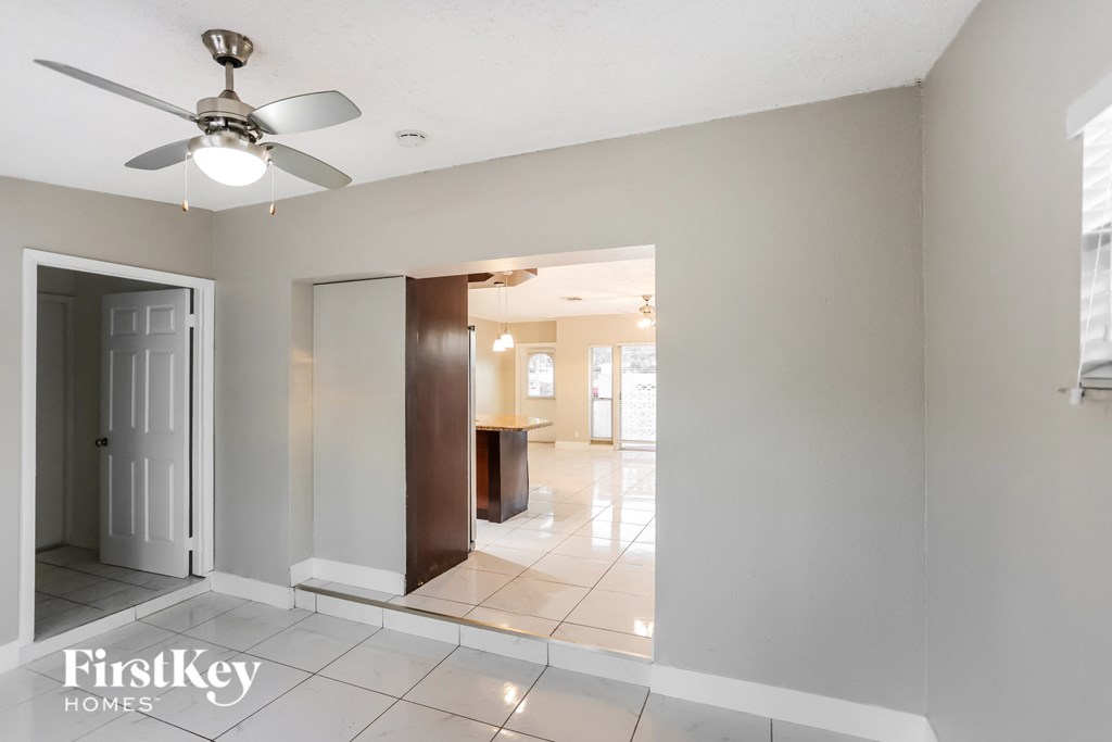 an empty living room with a ceiling fan and a tiled floor