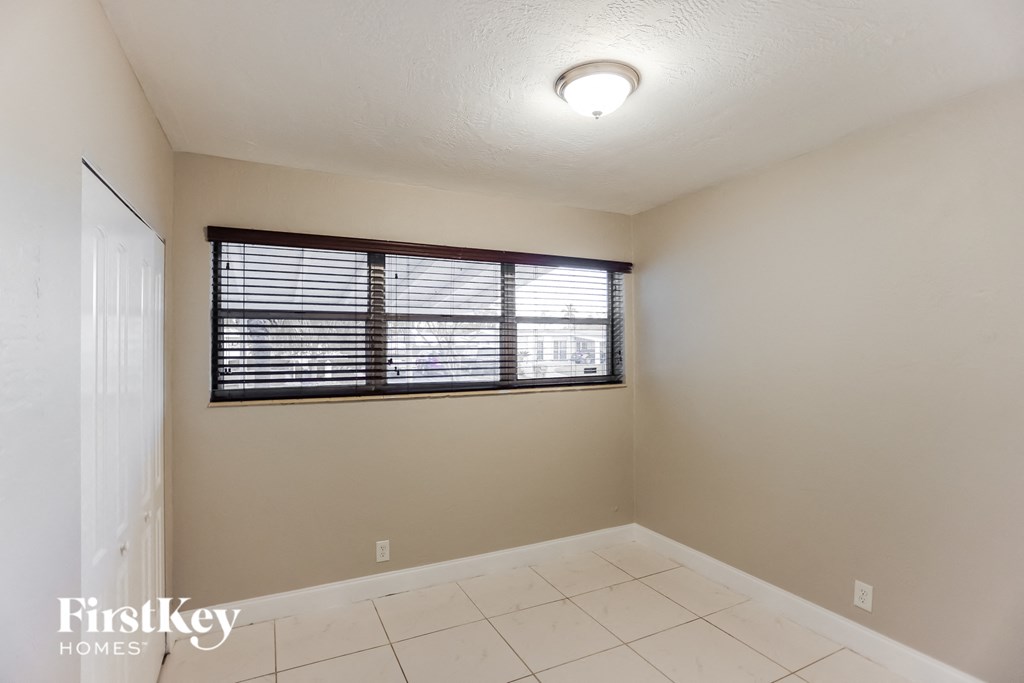 an empty living room with a window and a white tile floor