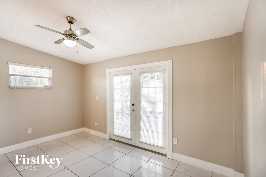 an empty living room with a ceiling fan and a door to a patio