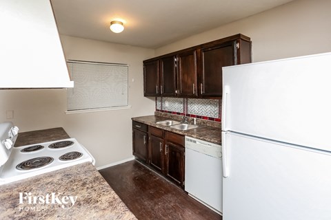 A kitchen with a white fridge, white stove and brown cabinets.