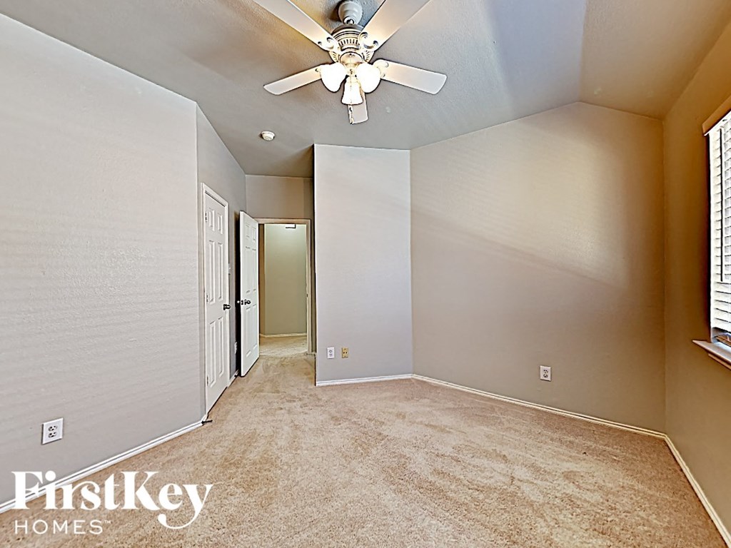 an empty bedroom with a ceiling fan and a door to a closet