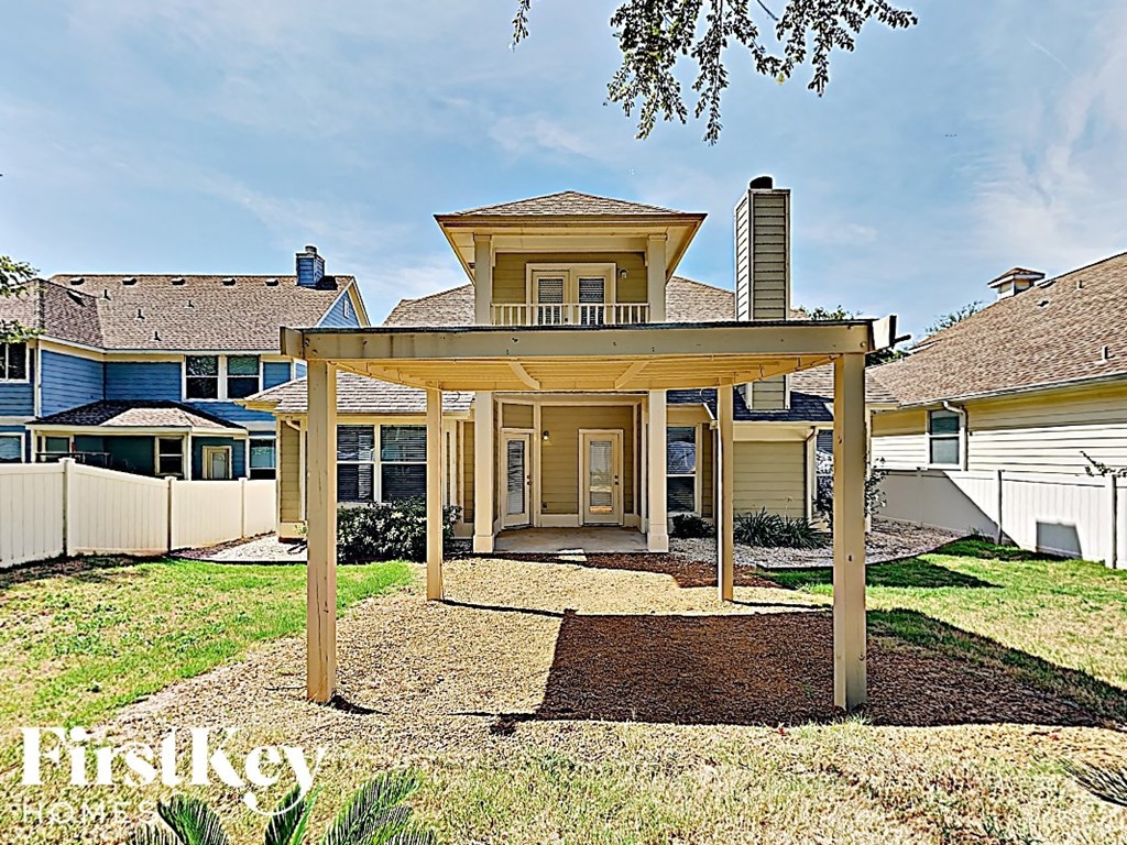 a pergola in front of a house with a yard
