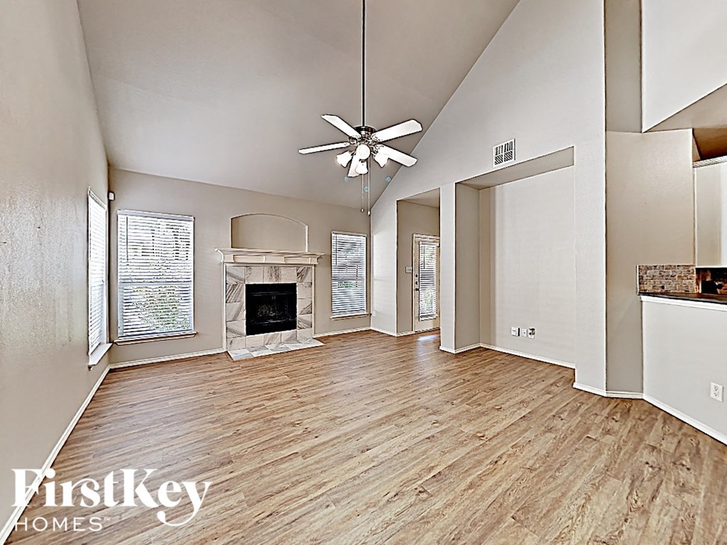 an open living room with a fireplace and a ceiling fan