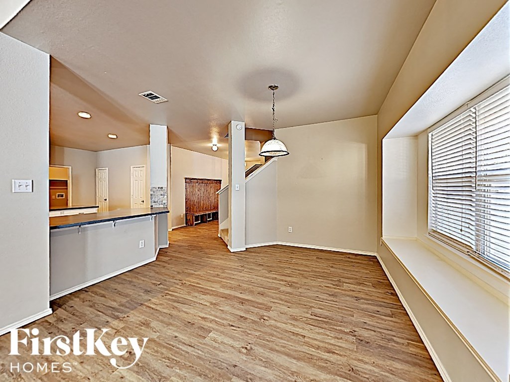 an open kitchen and living room with wood flooring and a large window