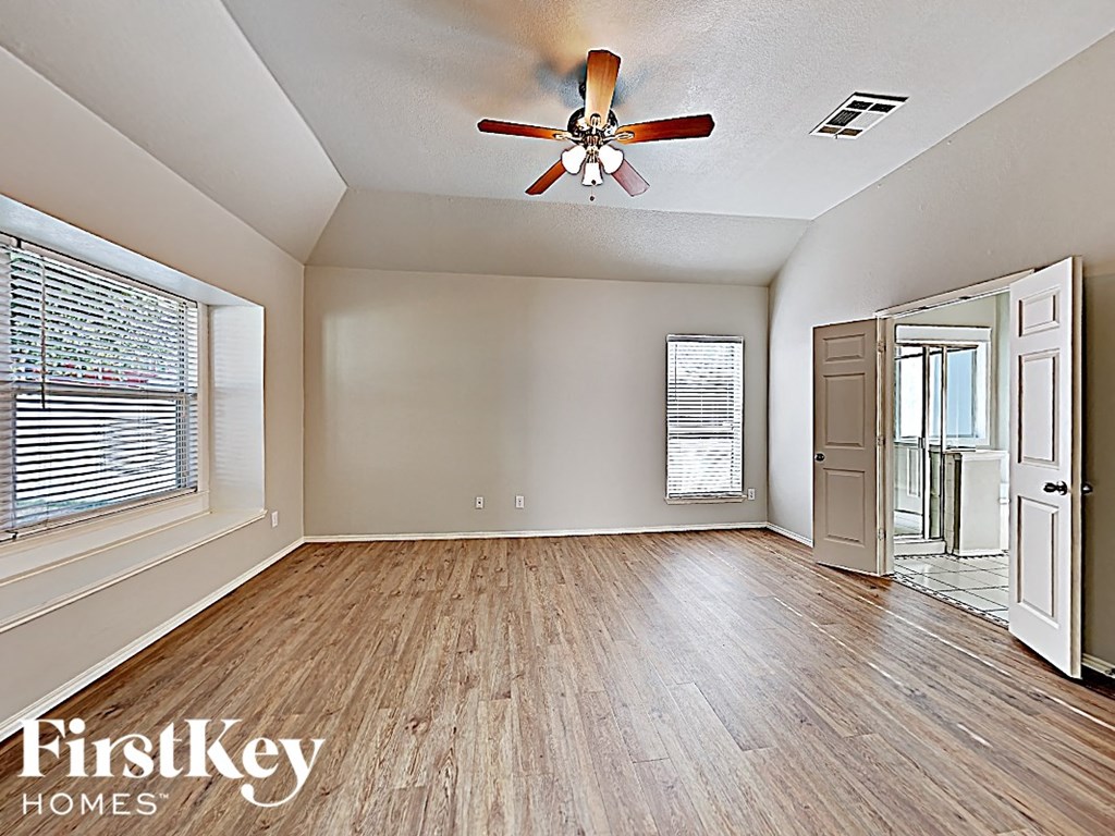 an empty living room with a ceiling fan and a window