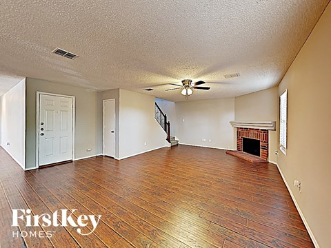 A spacious room with wood flooring and a fireplace.