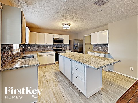 A kitchen with a granite counter top and wooden floors.