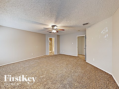 A room with a carpet floor and a ceiling fan.