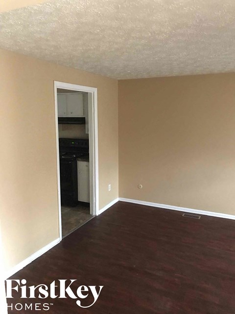 A room with a white door leading to a kitchen area.