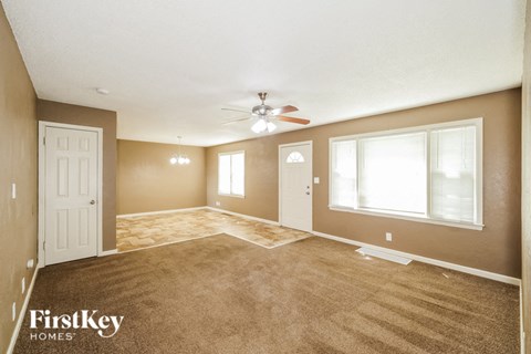 A spacious room with a carpeted floor and a ceiling fan.