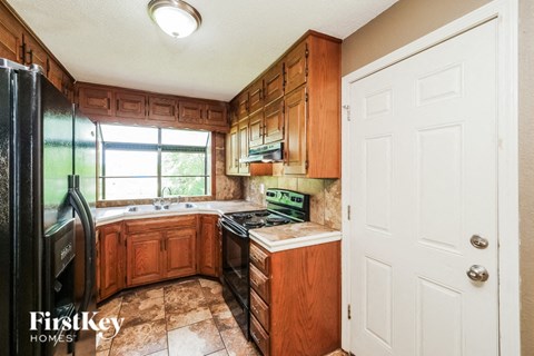 A kitchen with wooden cabinets and a black refrigerator.