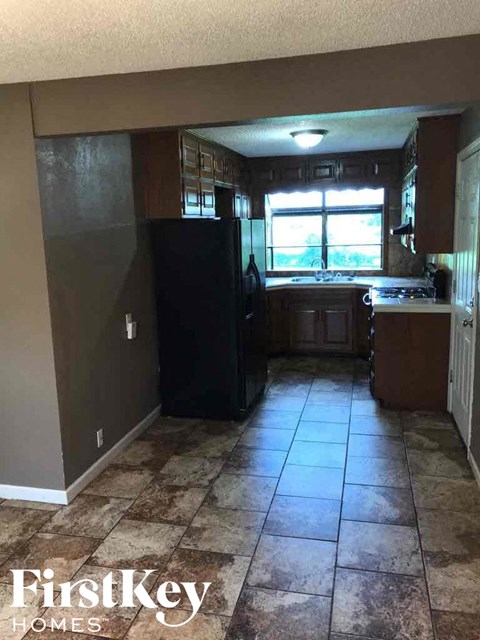A kitchen with a black refrigerator and brown cabinets.