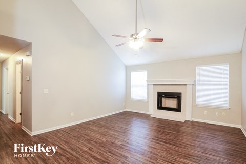 A spacious room with a fireplace and a ceiling fan.