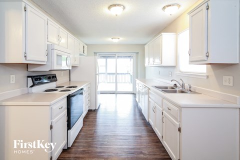 A kitchen with white cabinets and a stove top oven.