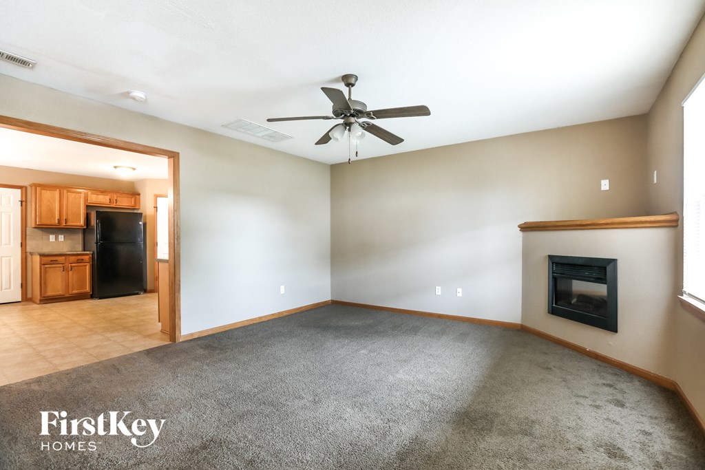 an empty living room with a fireplace and a ceiling fan