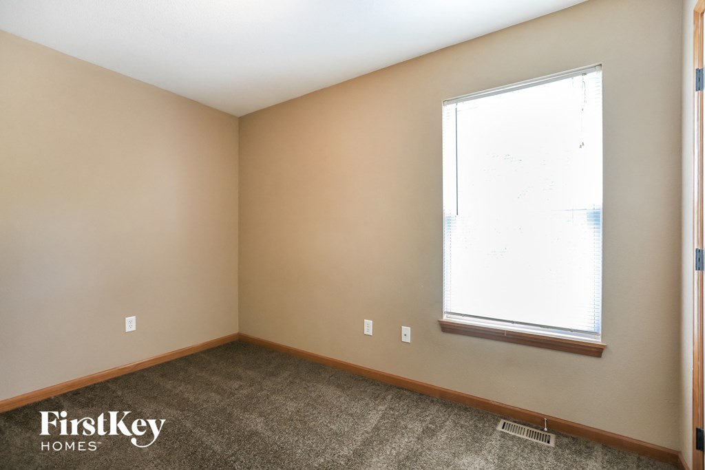 a bedroom with a large window and a carpeted floor