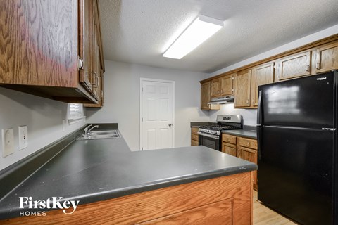 A kitchen with wooden cabinets and a black refrigerator.
