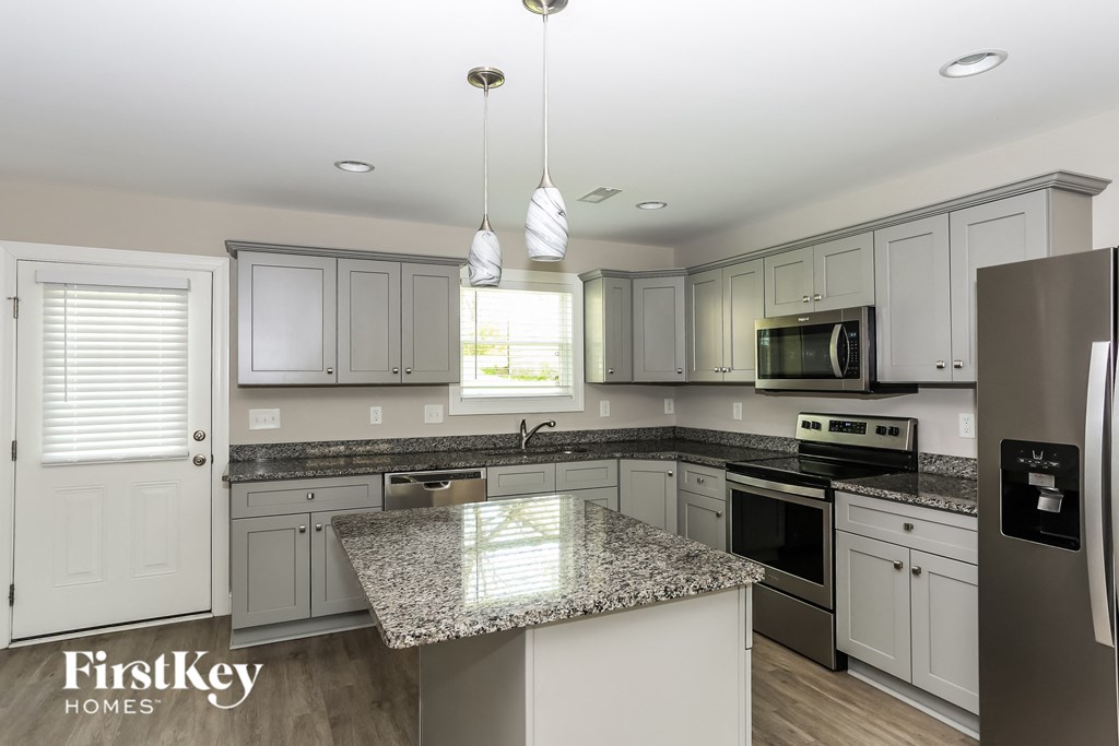 a white kitchen with granite counter tops and white cabinets
