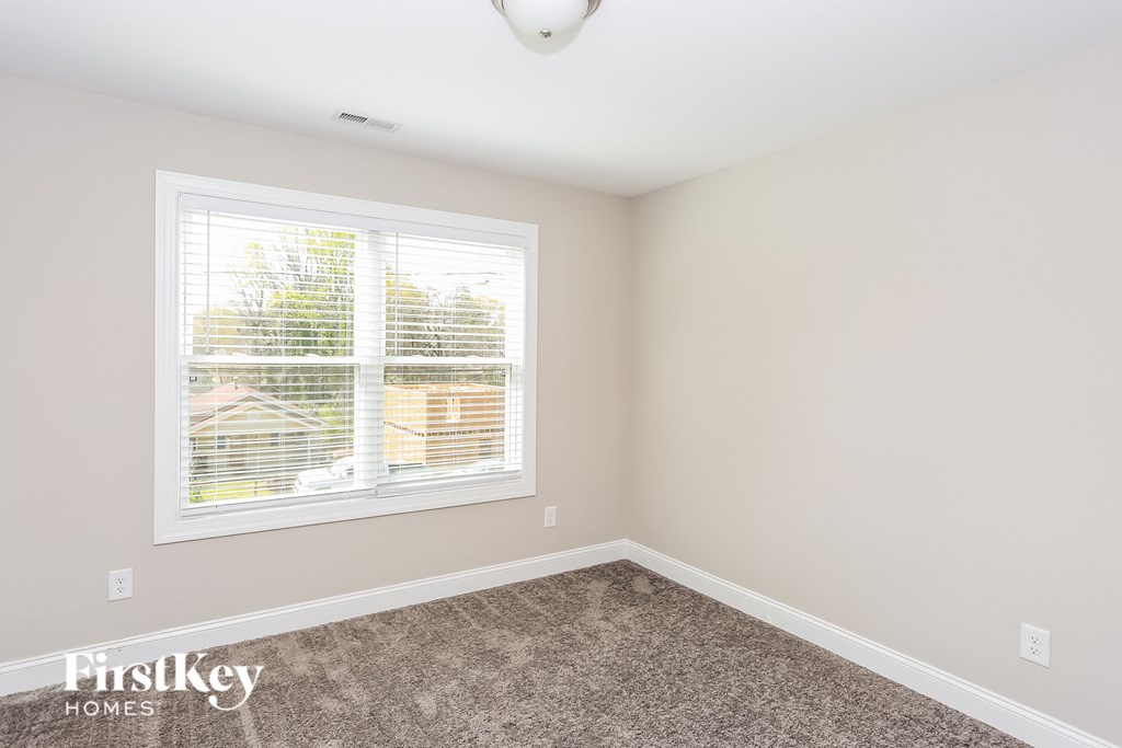 a bedroom with a window and a carpet