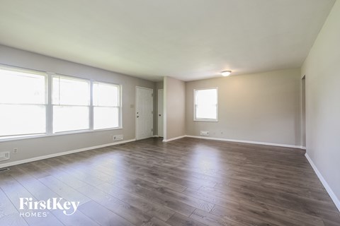 A spacious room with wooden flooring and large windows.